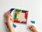 childs hand collects multicolored wooden mosaic on white background. child solves colorful tangram