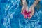 Childs hand holding a pink flower on a pool water