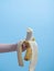 a childs hand holds a bitten banana on a blue