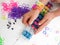 Childs hands making a multicoloured elastic band bracelet on a b