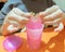 childs hands playing with pink shiny slime on the table. close-up