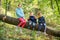 Childs sitting on Fallen Down Tree Trunk in autumn forest