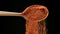 Chili powder falling from a wooden spoon
