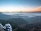 Chill morning with snow on rocky edge, valley full colorful mist