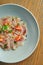 Chilled sea bass carpaccio with red onion, cherry tomatoes and hot chili peppers in a beige bowl on a wooden background. Close up