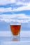 Chilled whiskey in a glass stands on an ice surface against a blurry sky.