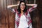 Chilling tanned girl touching her dark hair on wooden background. Photo of spectacular happy woman