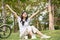 Chilling young Asian woman raising hands, sitting on grass, feeling freedom and carefree