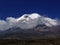 Chimborazo mountain tops covered in snow and surrounded with clouds under the blue sky in Ecuador