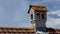 Chimney like a little house on the roof in front of grey clouds