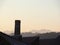 Chimney of old abandoned industrial complex. Work of industrial archaeology. In the background the profile of the mountains Alps