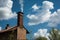 chimney, surrounded by fluffy clouds, against the backdrop of blue sky