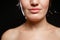 Chin and lips, part of the face and bare shoulders of a young woman on a black isolated background