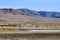 China. Herd of goats grazing in the colorful mountains of Tibet near small river