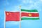 China and Suriname two flags on flagpoles and blue cloudy sky