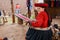 CHINCHERO, PERU- JUNE 3, 2013: Native Cusquena woman dressed in traditional colorful clothing works on a loom outside her house