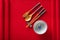 Chinese bowl, fork, spoon and chopsticks on red mat