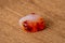 Chinese carnelian gemstone with smooth surface white orange and deep rep tones on wooden underground