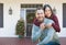 Chinese and Caucasian Young Adult Couple On Christmas Decorated Front Porch of House