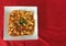 Chinese cuisine Mabo Tofu meal on white ceramic square dish with copy space red cloth table as background