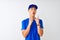 Chinese deliveryman wearing blue t-shirt and cap standing over isolated white background amazed and surprised looking up and