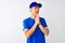 Chinese deliveryman wearing blue t-shirt and cap standing over isolated white background begging and praying with hands together