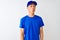 Chinese deliveryman wearing blue t-shirt and cap standing over isolated white background making fish face with lips, crazy and