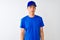 Chinese deliveryman wearing blue t-shirt and cap standing over isolated white background Relaxed with serious expression on face
