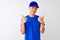 Chinese deliveryman wearing blue t-shirt and cap standing over isolated white background success sign doing positive gesture with