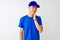 Chinese deliveryman wearing blue t-shirt and cap standing over isolated white background touching mouth with hand with painful