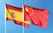 Chinese flag and Spanish flag on cloudy sky. waving in the sky