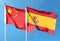 Chinese flag and Spanish flag on cloudy sky. waving in the sky