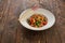 Chinese food, kung pao chicken in white plate with chopsticks on wooden table, top view and copy space