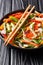 Chinese fresh vegetable salad with sesame and peanuts close-up on a plate. vertical