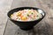 Chinese fried rice with vegetables and omelette in black bowl on wood
