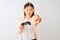 Chinese gamer woman playing video game using headphones over isolated white background pointing with finger to the camera and to