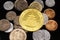 A Chinese gold coin with coins from Pakistan on a black reflective background