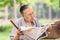 Chinese male senior reads a newspaper in a park, Beijing, China