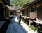 A Chinese man walking down a traditional village street lined by old granaries