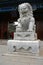 A Chinese marble stone lion sits in front of a traditional painted eave pavilion