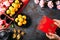 Chinese new year festival decorations. Woman hand holding pow or red packet, orange and gold ingots on a black stone background.