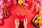 Chinese new year festival decorations. Woman hand holding pow or red packet, orange and gold ingots on a red background. Chinese