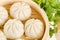 Chinese steamed buns in bamboo steamer basket with cilantro on w