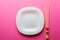 Chinese sticks white plate on a pink background