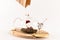 Chinese tea is poured from a paper bag into a glass teapot standing on a wooden stand on a white background