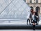 Chinese tourists taking selfie photos in front of the Louvre Pyramid. Louvre pyramid is one of the main attractions of Paris