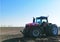 Chinese tractor Massey Ferguson MF8737 against the background of a plowed field in spring