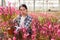 Chinese woman gardener is standing with flowers Oenothera lindheimeri in orangery