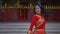 A Chinese woman in a red suit walking in front of the Chinese temple