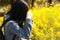 Chinese woman taking pictures of yellow flowers